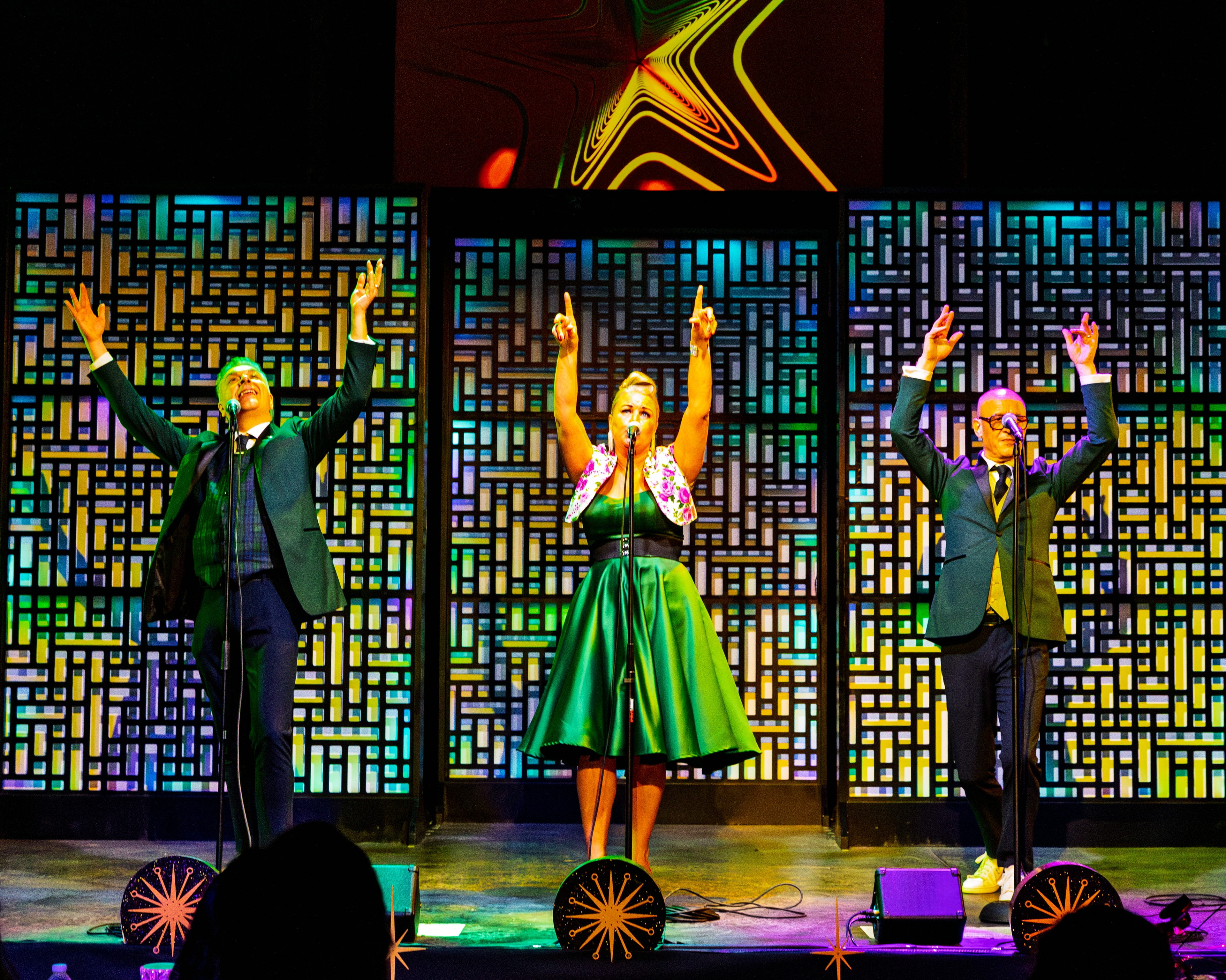 The Fabulous Lounge Swingers — trio with arms raised against colorful backdrop