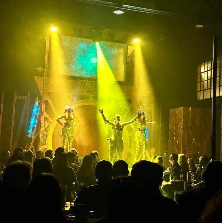 Saucy Jack and the Space Vixens 2022 — performers on stage with yellow green lighting